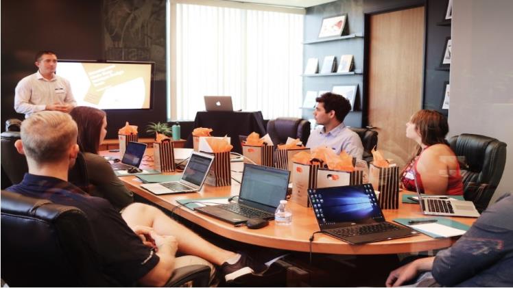 Tips for Leveraging Enterprise Search for Business Intelligence A team leader discussing the benefits of enterprise search while a team sits at a table with laptops.